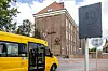 Billedet viser Byskolen i Nakskov med en gul skolebus i forgrunden. Byskolen er en stor bygning i røde mursten og bygget i en flot byggestil med mønstre i stensætningen.