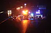 Nød- og redningskøretøjer med blink på mørk motorvej ved ulykke.