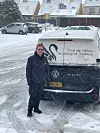 Person står ved Volkswagen ID. Buzz varebil i snevejr på parkeringsplads.
