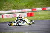 En enkelt gokart i høj fart gennem et sving på en udendørs racerbane.