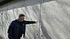 Søren Hansen, Ravnsborghallen, peger på detalje i grå betonvæg udendørs
