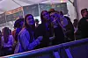 Tre unge kvinder poserer ved rækværk i farverigt oplyst festivaltelt.