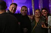 Smilende gruppe voksne står i et oplyst festivaltelt om aftenen
