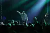 Rapper peger mod publikum på mørk scene badet i grønt lys