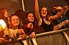 Unge publikummer ved rækværk jubler og peger mod scenen under koncert.