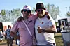 To smilende festivalgæster med arme om hinanden på en solrig plads