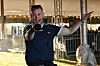 Mand i Adidas T-shirt rækker ud mod kameraet i et lyst festivaltelt.