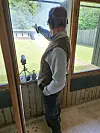 Mand med høreværn peger ud mod et mål gennem et vindue i en skydebane.