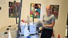 En kvinde står i et atelier med malerier, staffelier og kunstudstyr.