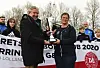 Personer holder en pokal foran et banner med DBU Lolland-Falster ved en udendørs prisoverrækkelse.