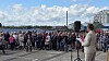 Taler ved mikrofon foran en stor menneskemængde på en havneplads.