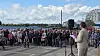 Taler ved mikrofon foran en stor menneskemængde på en havneplads.