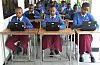 Skoleelever i uniform arbejder ved bærbare computere i et klasselokale.
