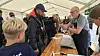 Mennesker taler ved en informationsstand under et telt.