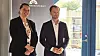 To personer står foran et ministerium ved siden af en glasdør.