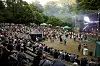 Stort publikum ser koncert på en udendørsscene omgivet af træer i Hylddalen.