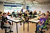 Elever arbejder sammen ved borde i et farverigt klasselokale.