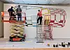 To personer arbejder på en stor køretøjsillustration fra lift og stige i et værksted.