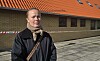 Person foran en murstensbygning med rødt tag og afspærringsbånd.