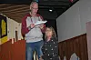 Jørgen Petersen læser fra et manuskript på en dekoreret amatørscene, mens en medspiller sidder ved siden af.