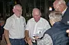 Gruppe ældre mennesker taler sammen ved en indendørs sammenkomst.