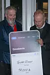 To mænd holder en stor tavle med en hilsen og en pengegave på 500.000 kroner.